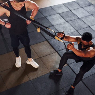 Personal trainer is on job. African american man with white guy have workout day in gym.